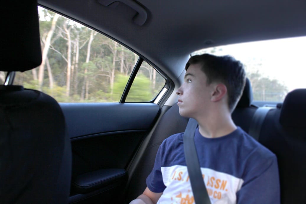 teenage boy gazing out the window in the back seat 2026 03 17 04 25 55 utc