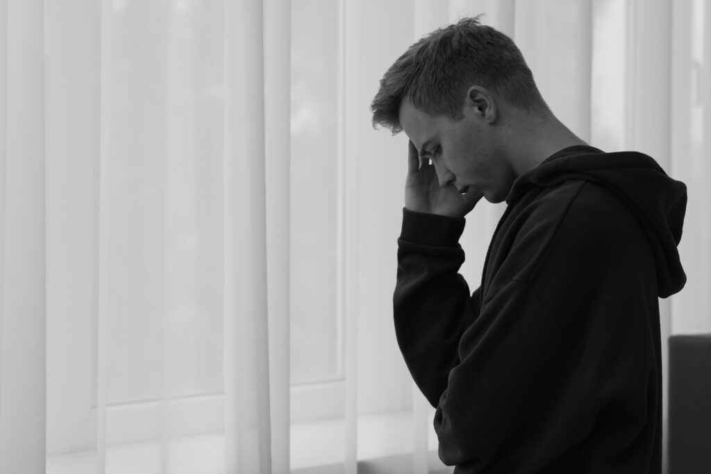 pensive young man in profile standing by a window 2026 09 25 03 34 33 utc